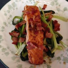 Baked salmon with bacon on a bed of tatsoi